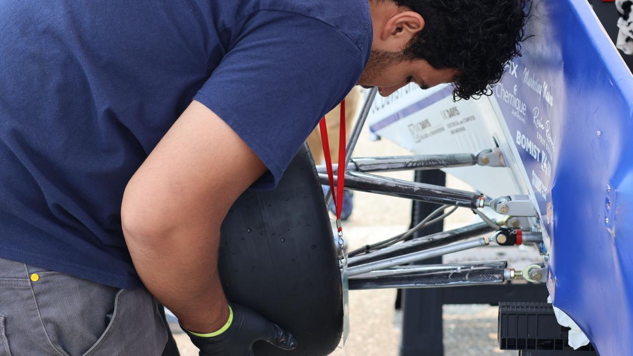 Student installing tire onto car